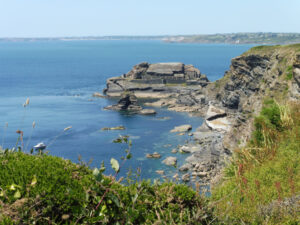 Vue depuis les falaises du GR34 sur le fort des Capucins, ouvrage militaire posé sur un îlot rocheux au pied des falaises schisteuses, presqu'île de Crozon, avec la rade de Brest en arrière-plan