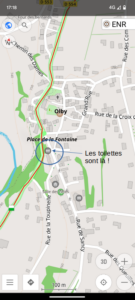 Capture d'écran de l'application OsmAnd affichant la carte du village d'Olby. Un cercle bleu et une flèche annotation indiquent l'emplacement des toilettes publiques, Place de la Fontaine, avec le texte « Les toilettes sont là ! ».