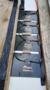 Face arrière de quatre panneaux solaires Mazava CNC85X115-12 câblés en série, calés dans un cadre en bois et maintenus avant collage des sangles