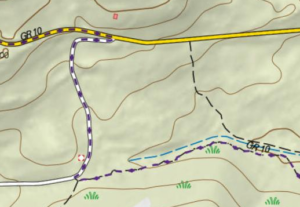 Extrait de carte topographique numérique montrant un tronçon du GR10 espagnol, représenté par un tracé en tiretés violet et blanc, bifurquant depuis une route jaune pour descendre vers un cours d'eau à sec signalé en bleu, avec des courbes de niveau marron sur un fond de relief ombré.