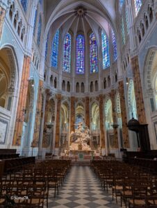 Intérieur de la Cathédrale Notre-Dame de Chartres, avec son chœur, ses vitraux colorés, son autel et ses statues, vu depuis la nef centrale.