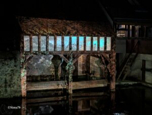 Lavoir en pierre au bord de l’Eure, éclairé par des lumières bleutées qui créent des jeux d’ombres et de reflets dans l’eau.