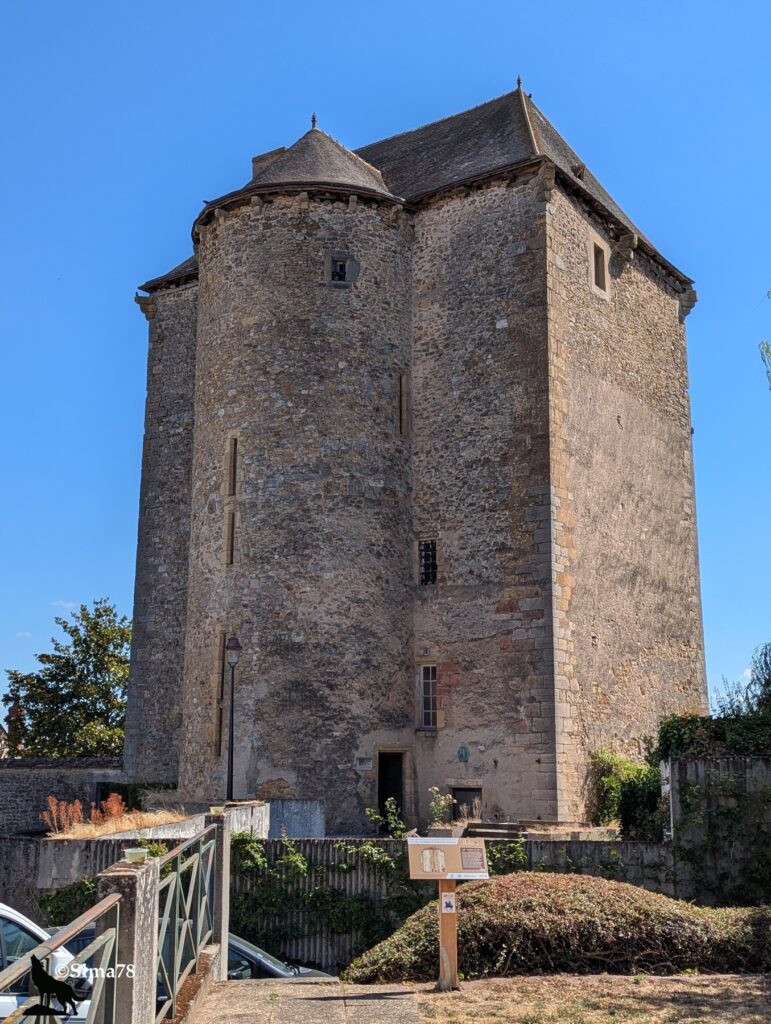 Photographie du Donjon des Chauvigny à La Châtre, imposante tour médiévale en pierre à la base ronde et au corps carré, sous un ciel bleu dégagé.